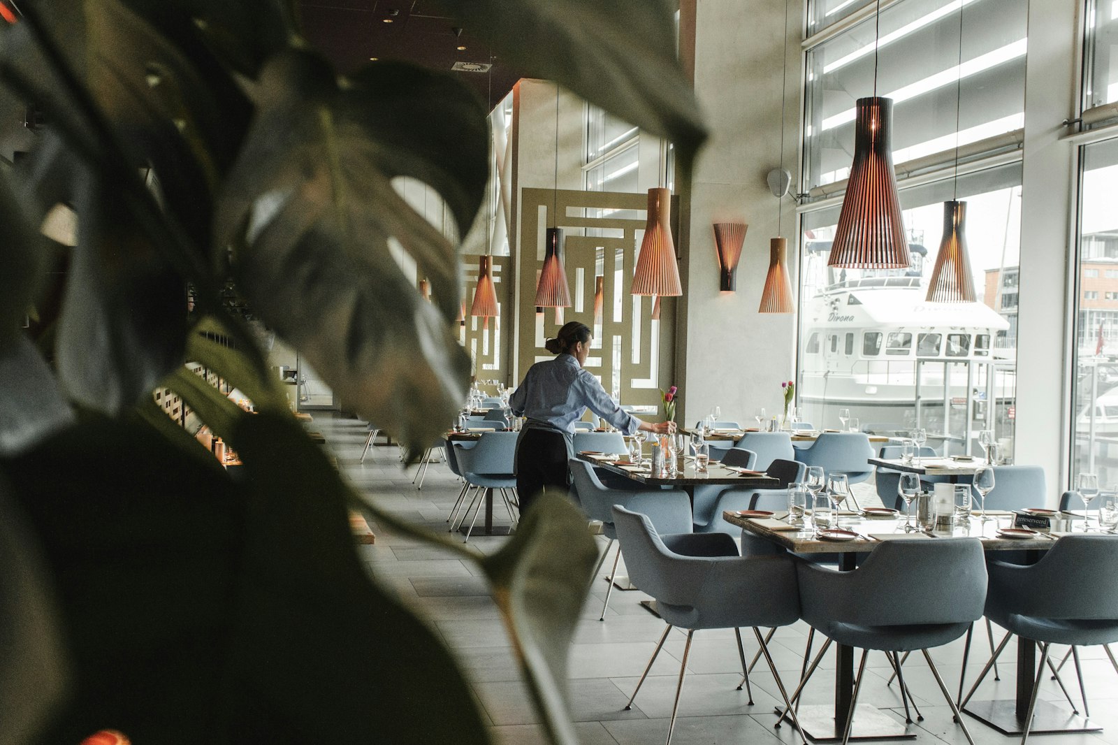 A server setting a table in a bright restaurant dining room