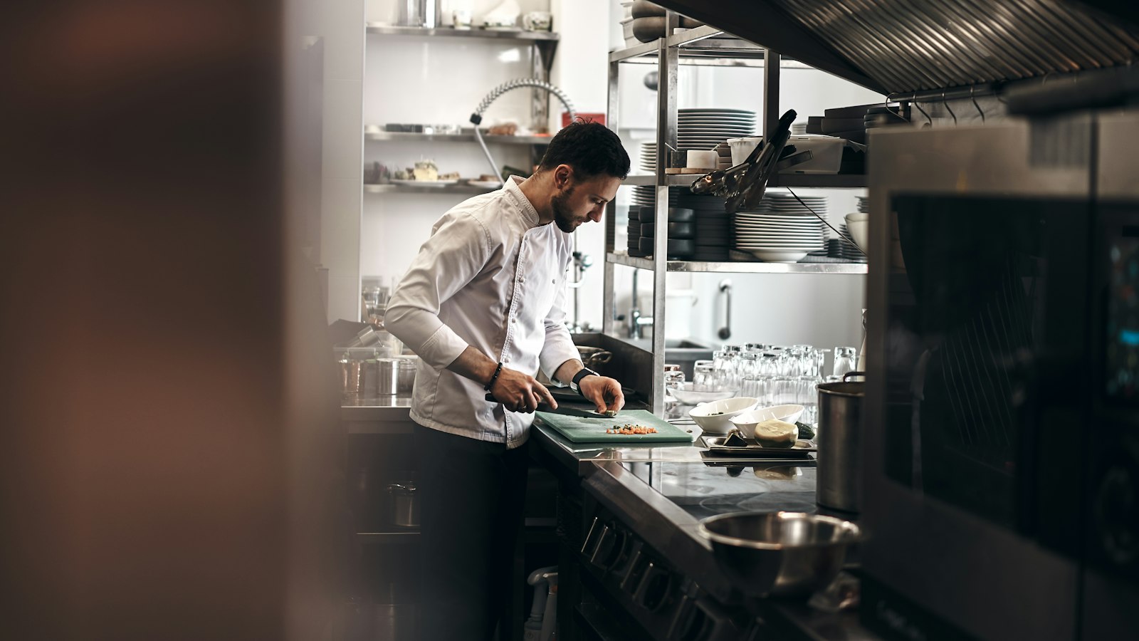 A chef plating food at a restaurant kitchen pass