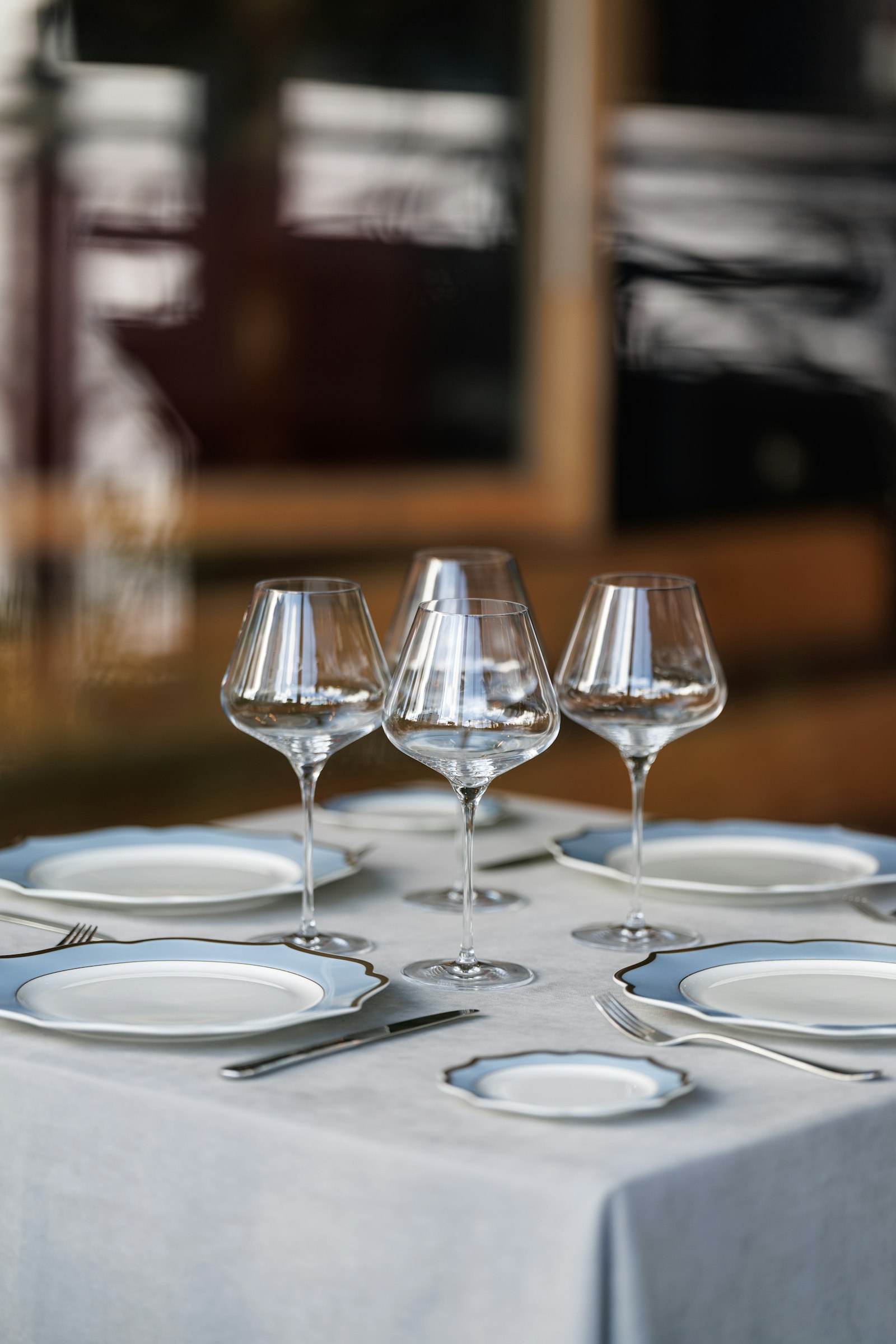 A set table with wine glasses and white plates